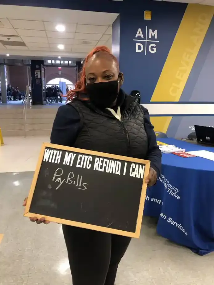 Woman with mask on holding a sign 