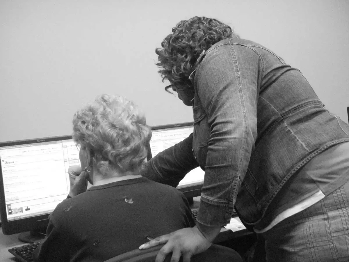 Two people looking at a computer in a black and white photo