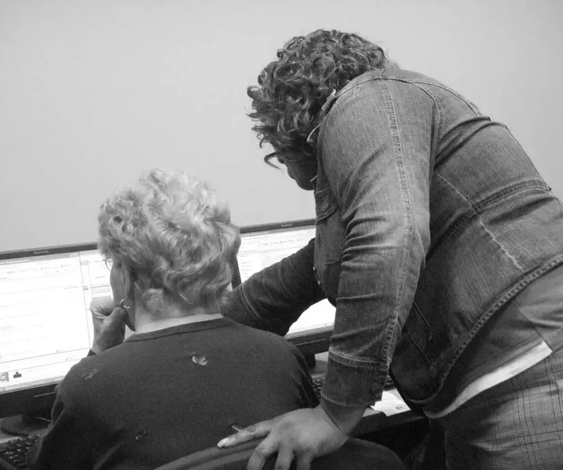 Two people looking at a computer in a black and white photo